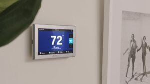 Digital smart thermostat displaying 72° with cooling mode active and set point of 71° on white wall.
