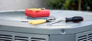 Screwdrivers and hand tools arranged on top of an HVAC air conditioning unit for maintenance and repair work.